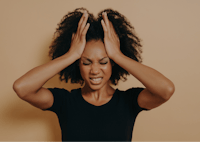 a woman with afro hair covering her head with her hands