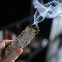 a person holding a sage stick with smoke coming out of it